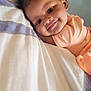 baby, child, smile, face, hair_bow, curly_hair, bed, pillow, blanket, clothing, infant, portrait, cute, happy, lying_down, indoors, soft_light, pastel_colors, peaceful, young