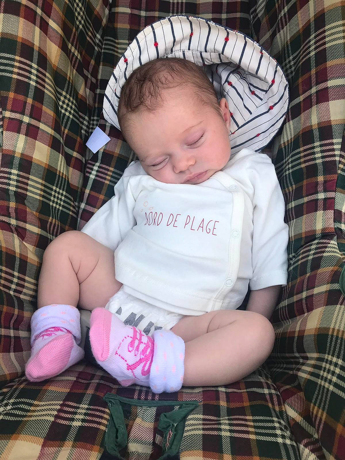 Colyne participe au concours pour gagner de l'argent avec cette photo : baby, baby_products, baby_toddler_clothing, cheek, child, design, headgear, leg, pattern, person, pink, plaid, product, sitting, skin, tartan, textile, toddler