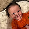 baby, smile, orange_clothing, cushion, love_pattern, carpet, infant, face, happy, child, indoor, portrait, cute, young, person, cozy, closeup, skin, hair, expression