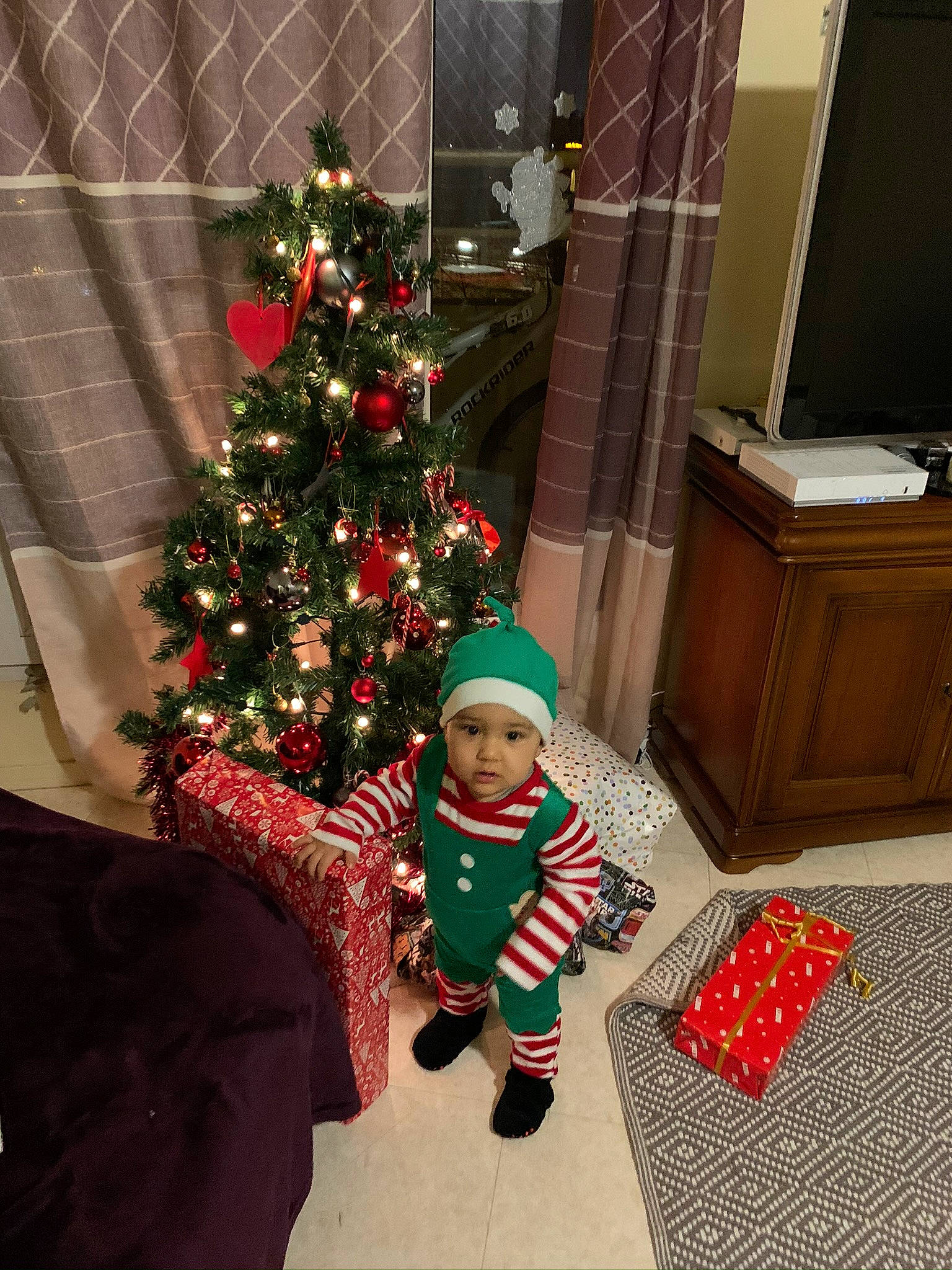 Ilian participe au concours pour gagner de l'argent avec cette photo : child, christmas, christmas_decoration, christmas_eve, christmas_lights, christmas_ornament, christmas_stocking, christmas_tree, event, fir, headwear, holiday, holiday_ornament, home, interior_design, person, pine_family, plant, room, toddler