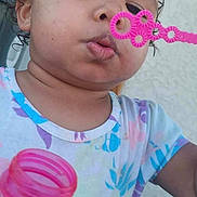 Serenity is registered to the contest to win money with this photo: toddler, child, bubble_wand, bubble_bottle, blowing_bubbles, curly_hair, colorful_shirt, outdoor, close_up, face, expression, hand, play, summer, fun, young_child, curious, casual_clothing, person, daylight