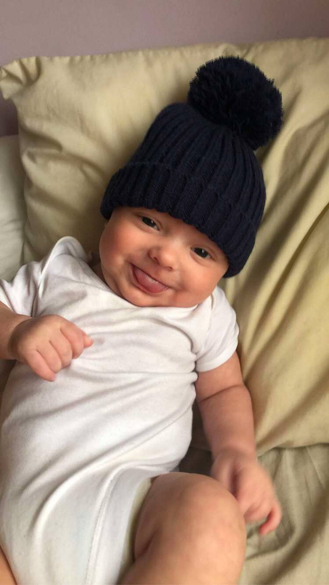 Taylor is registered to the contest to win money with this photo: baby, beanie, cap, cheek, child, comfort, eye, happy, headwear, human_leg, joy, knee, knit_cap, linens, lip, nose, person, smile, textile, thigh