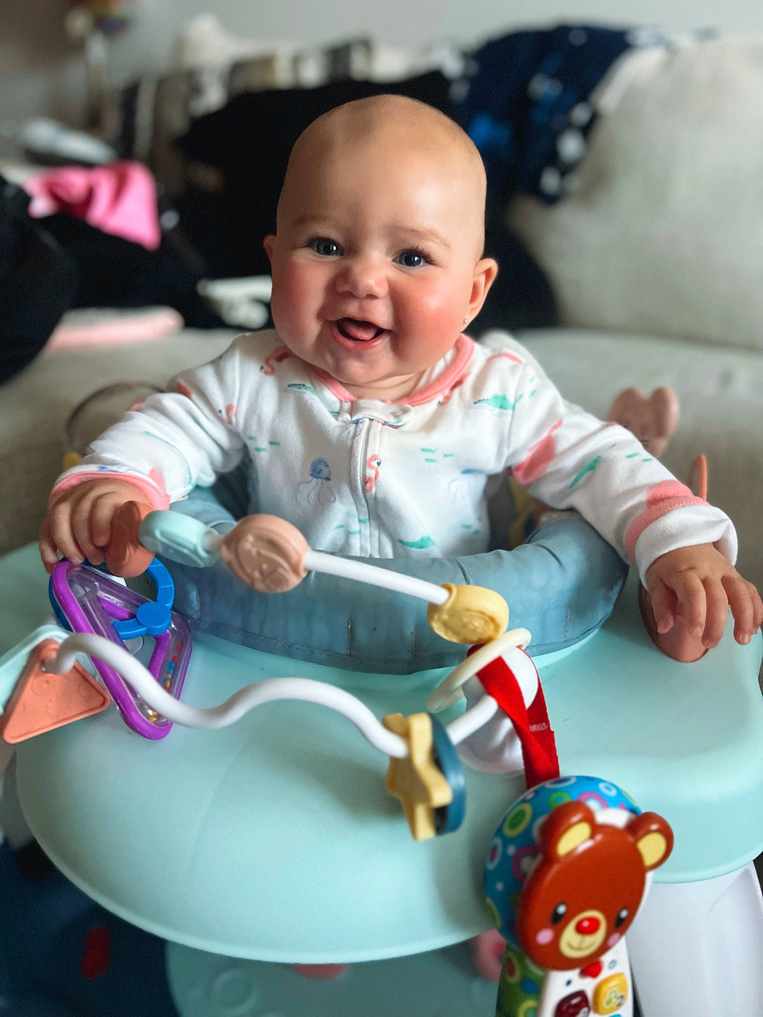 Emilia is registered to the contest to win money with this photo: baby, baby_playing_with_toys, baby_products, baby_toddler_clothing, baby_toys, cheek, child, comfort, finger, fun, happy, head, human_body, person, product, riding_toy, room, sitting, skin, smile