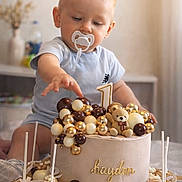 Kayden participe au concours pour gagner de l'argent avec cette photo : child, baby, toddler, pacifier, birthday_cake, first_birthday, number_one_candle, teddy_bear, gold_decor, cream_cake, cake_pop, sweets, celebration, indoor, portrait, curious, hand_reaching, wooden_board, blurred_background, smile