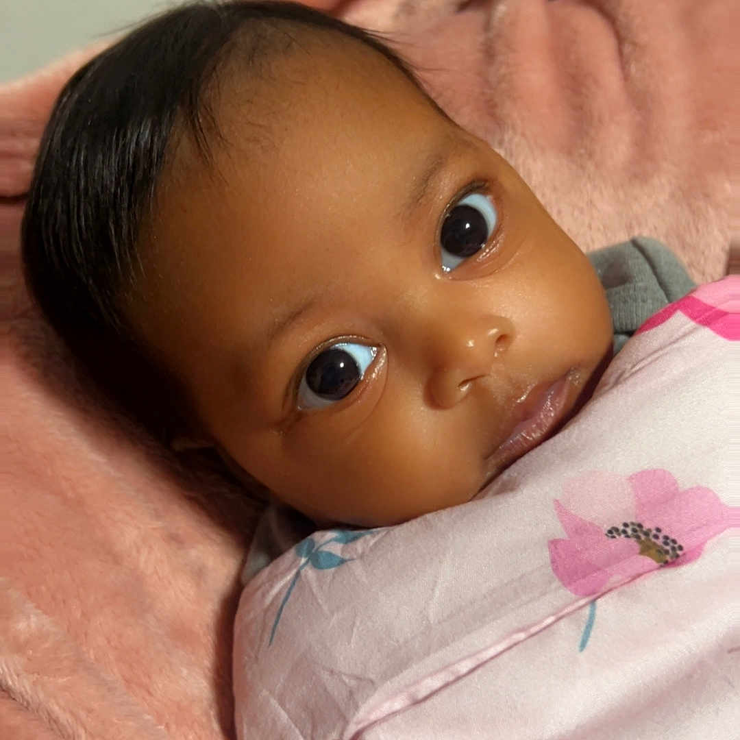 Kanyla joined the competition — help win amazing prizes! baby, infant, child, portrait, wide_eyes, looking_at_camera, dark_hair, brown_skin, floral_blanket, pink_blanket, wrapped, lying_down, cozy, indoor, bedroom, soft_lighting, close_up, face, cute, photography