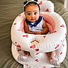 baby, infant, child, sitting, inflatable_seat, pink, white, bunny_prints, pigtails, hair_bows, blue_collar, striped_clothing, indoor, cute, wide_eyes, plastic_shoes, bed, blanket, portrait, adorable