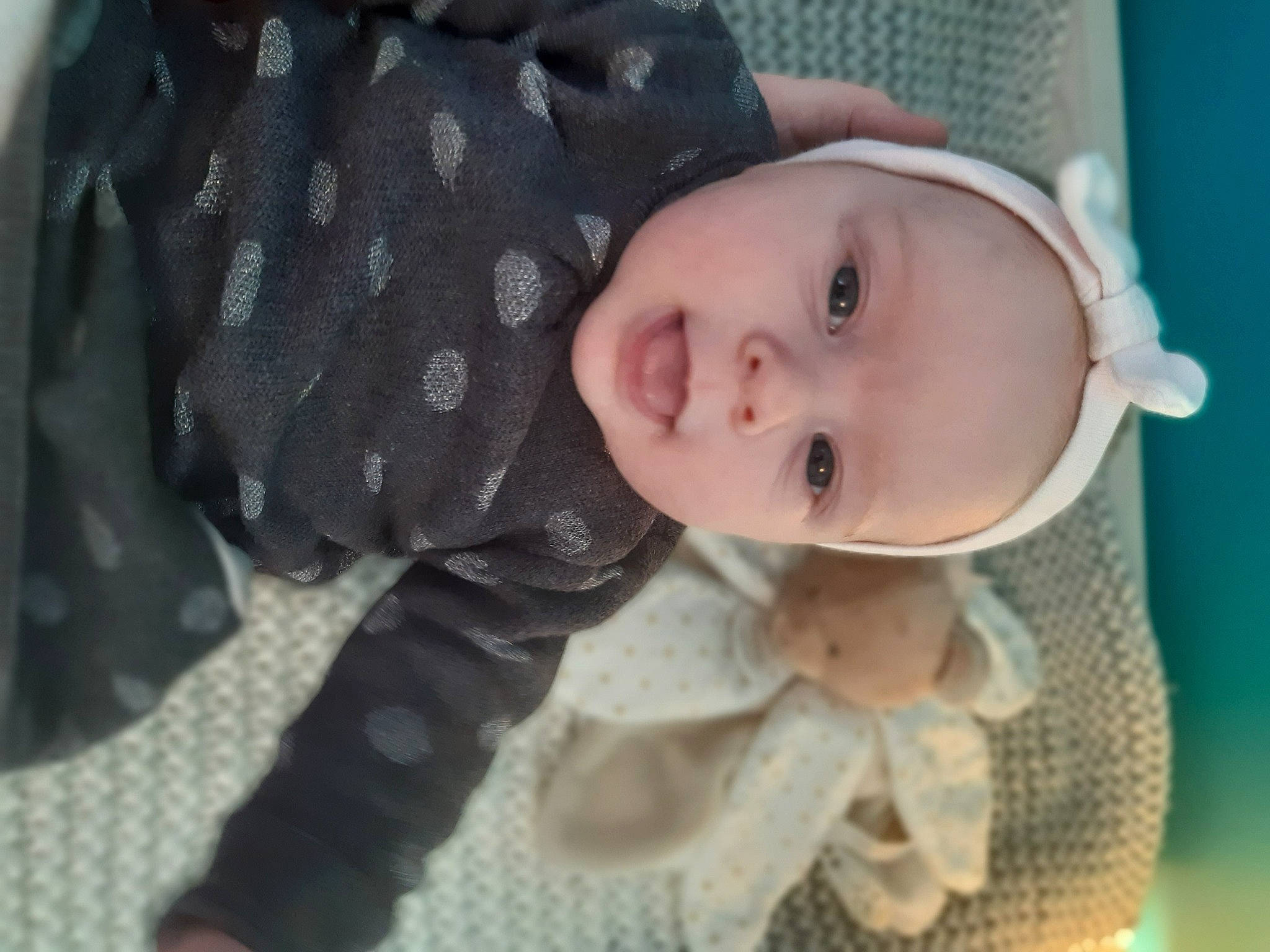 Mya participe au concours pour gagner de l'argent avec cette photo : baby, baby_products, baby_toddler_clothing, cheek, child, comfort, happy, headwear, iris, lip, nose, outerwear, pattern, person, product, sitting, skin, sleeve, smile, textile