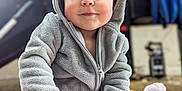 Phoebe is registered to the contest to win money with this photo: bodypart, clothing, coat, face, finger, hand, happy, hat, head, hood, hoodie, jacket, knitwear, person, photography, portrait, sitting, smile, sweater, sweatshirt