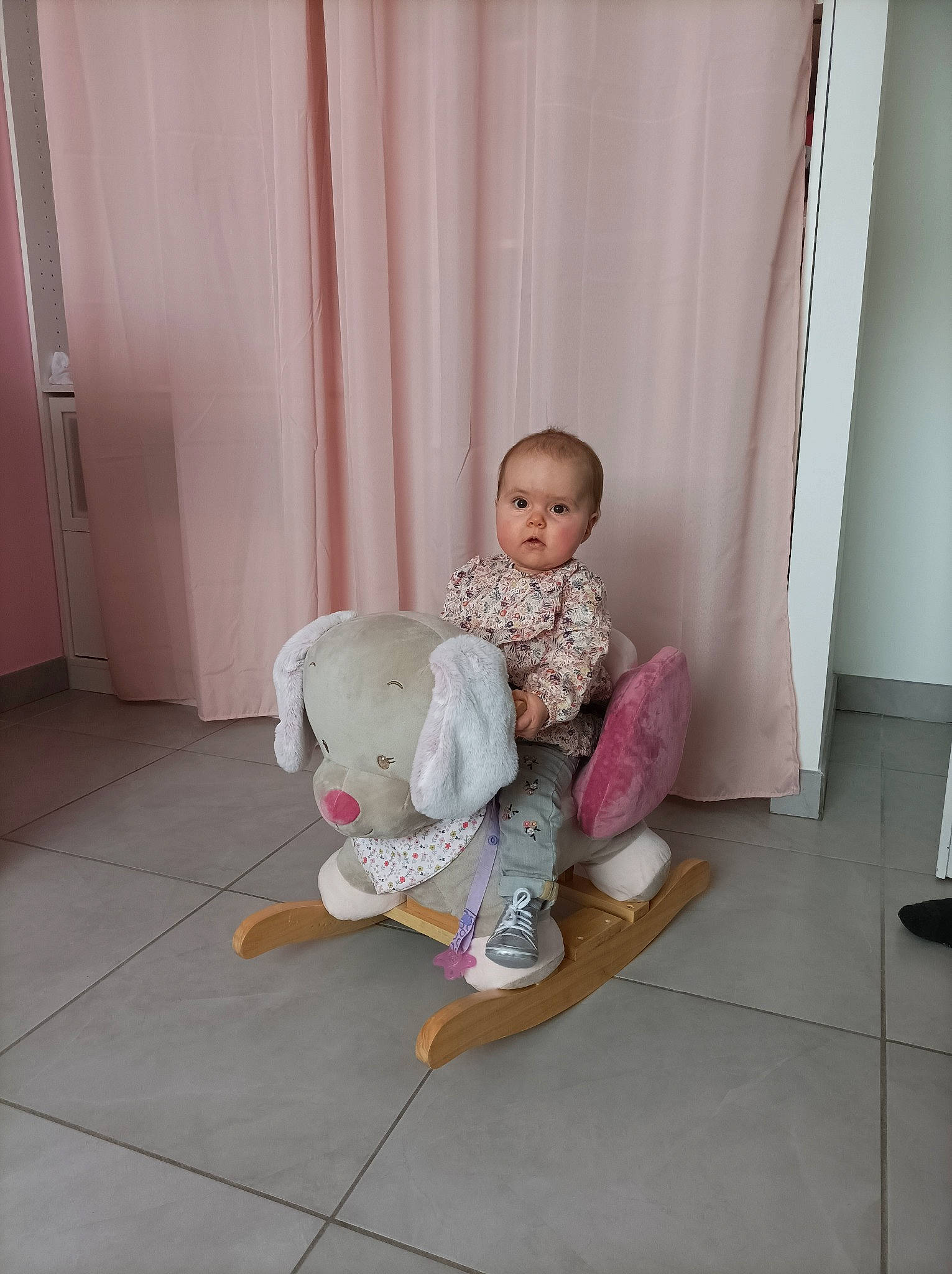 Louane participe au concours pour gagner de l'argent avec cette photo : baby, baby_products, baby_toddler_clothing, barefoot, chair, comfort, curtain, door, floor, flooring, foot, hardwood, human_leg, knee, person, pink, room, sock, thigh, toddler
