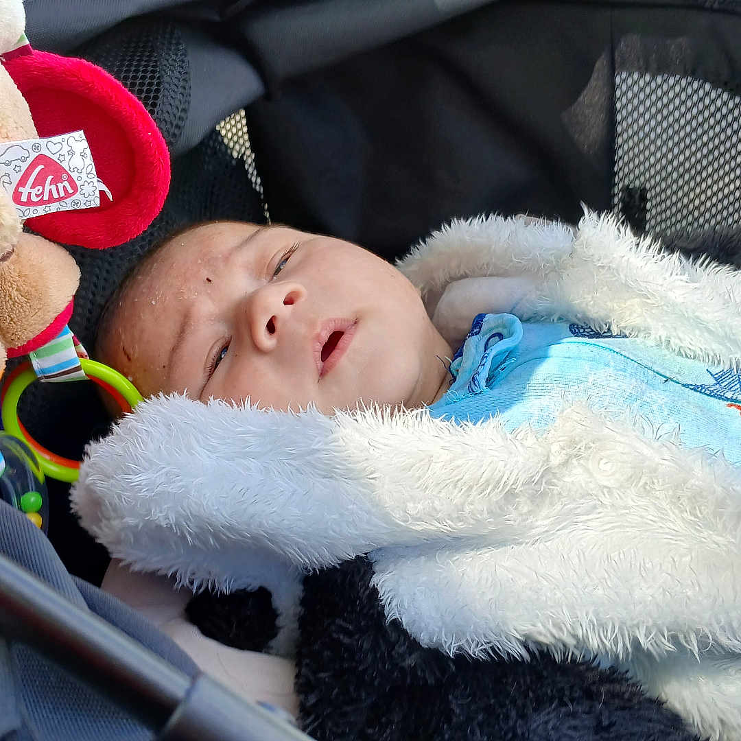 Eren participe au concours pour gagner de l'argent avec cette photo : baby, bed, blanket, car, car_interior, clothing, face, furniture, gun, hat, head, newborn, person, photography, portrait, sleeping, stroller, transportation, vehicle, weapon