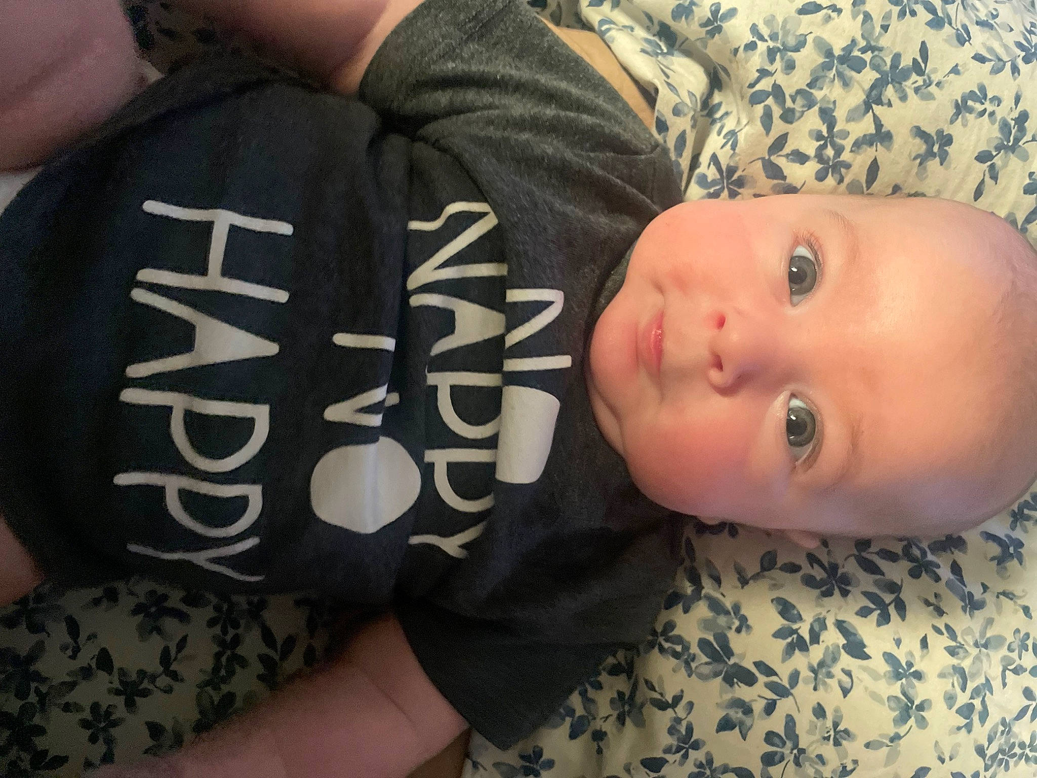 Luca is registered to the contest to win money with this photo: baby, baby_toddler_clothing, cheek, child, comfort, elbow, finger, flooring, font, nail, pattern, person, room, sitting, sleeve, t_shirt, thumb, toddler, wood, wrist