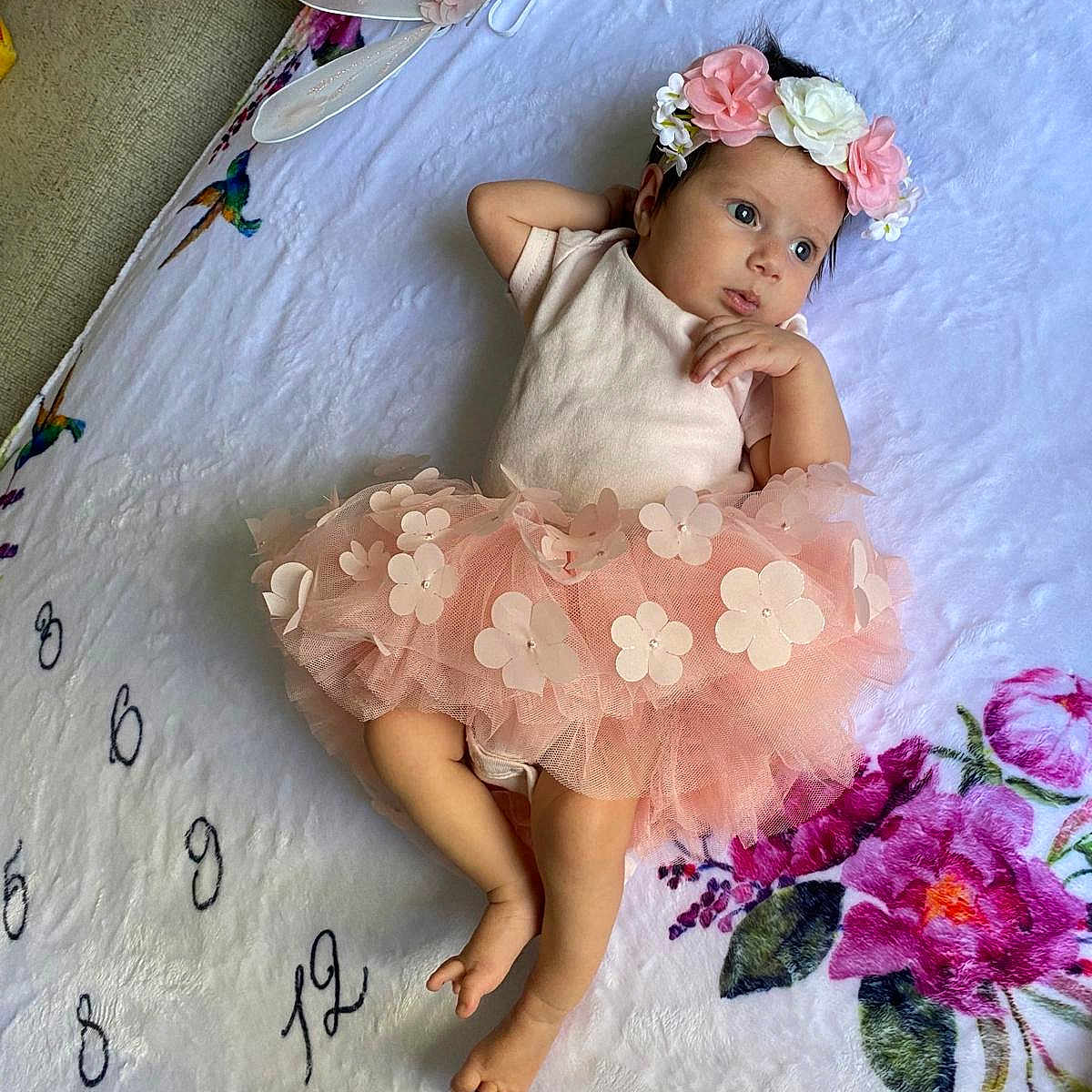 Isabella is registered to the contest to win money with this photo: baby, clothing, dress, face, flower, flowerarrangement, flowerbouquet, furniture, hair, hat, head, infantbed, person, petal, photography, plant, portrait, sitting, sleeve, text