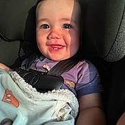 Axial joined the competition — help win amazing prizes! baby, child, car_seat, blanket, smile, teeth, sunlight, shadow, purple_shirt, infant, seatbelt, cute, happy, indoor, portrait, close_up, person, young_child, warm_light, cozy