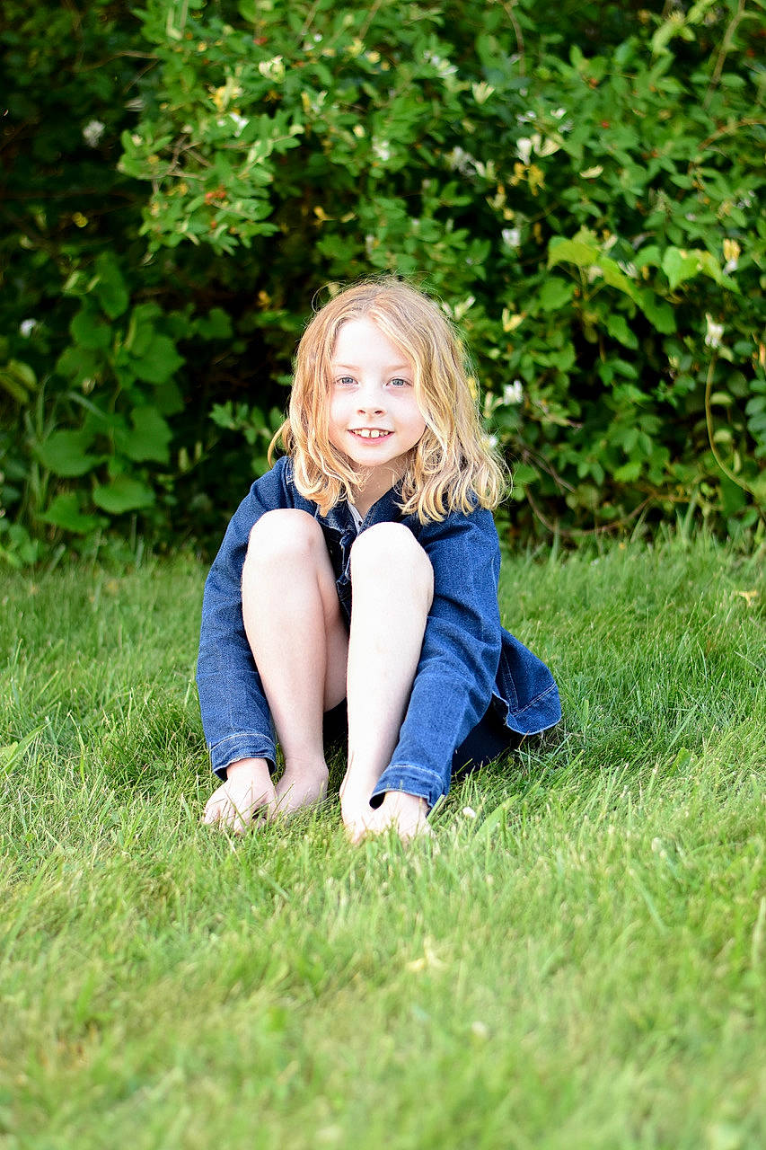 Camryn is registered to the contest to win money with this photo: brown_hair, denim, electric_blue, flash_photography, fun, grass, grassland, happy, human_leg, joy, leisure, long_hair, meadow, natural_landscape, people_in_nature, person, plant, prairie, sitting, smile