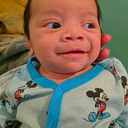 Rolando joined the competition — help win amazing prizes! baby, infant, face, child, clothing, mickey_mouse, onesie, hand, smile, happy, looking_away, cute, skin, eyes, person, portrait, indoors, soft_texture, fabric, support