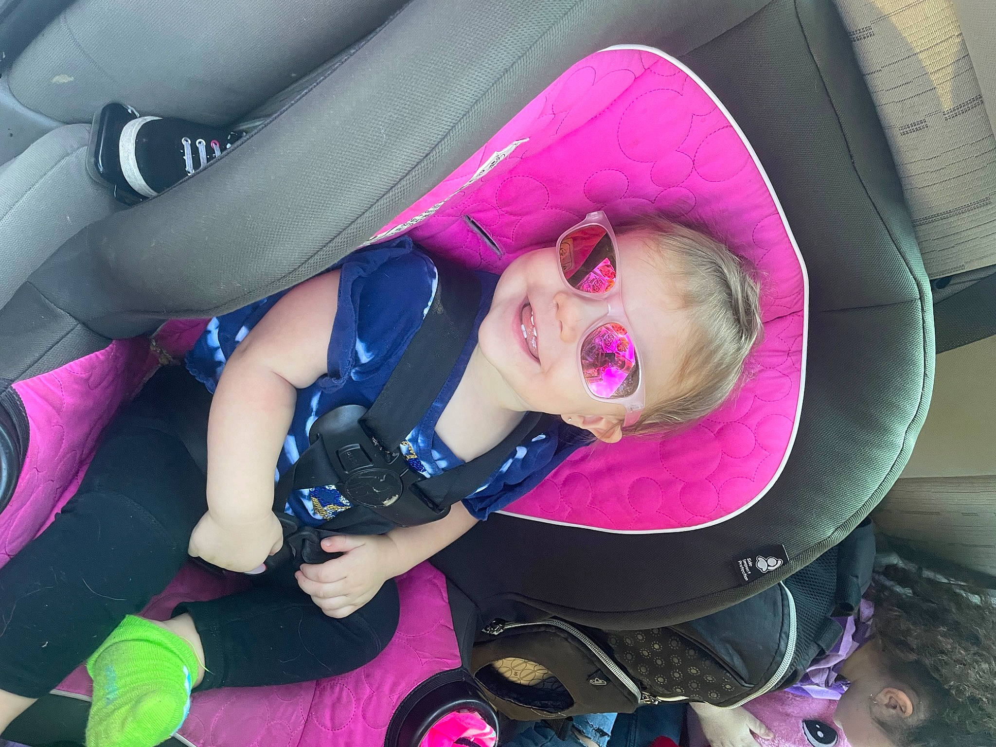 Lillyanna is registered to the contest to win money with this photo: arm, auto_part, baby_carriage, child, comfort, cool, eyewear, fun, goggles, headgear, human_body, joy, mouth, people, person, pink, product, purple, shoe, sunglasses