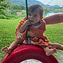 toddler, child, tire_swing, orange_towel, rope, outdoor, green_grass, lake, mountains, adult_hands, summer, playground, nature, barefoot, curious, daylight, person, recreation, fun, scenic
