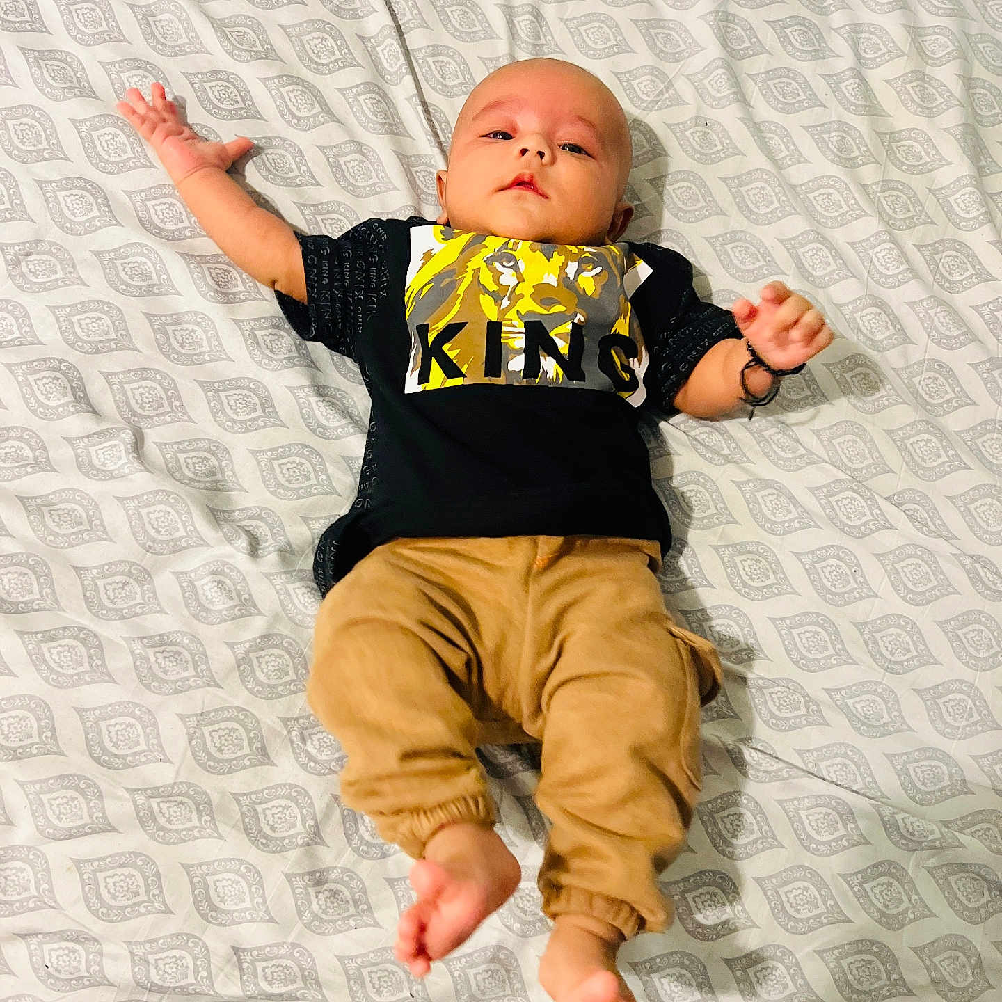 Raja Essa joined the competition — help win amazing prizes! baby, barefoot, bed, blanket, casual, child, clothing, cute, graphic_tee, indoors, infant, lion, lying_down, pants, patterned_bedspread, person, relaxed, shirt, text, young