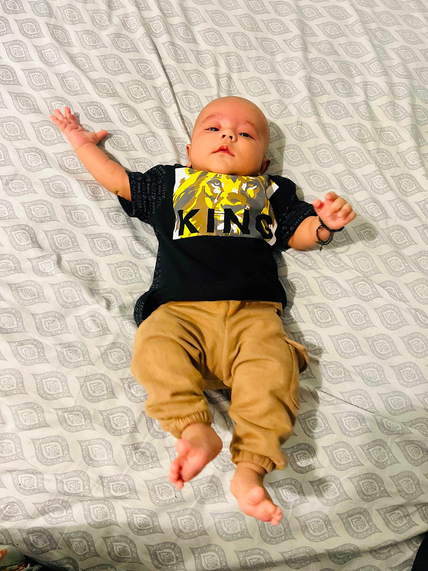 Raja Essa joined the competition — help win amazing prizes! baby, infant, bed, blanket, clothing, pants, shirt, graphic_tee, lion, text, person, barefoot, lying_down, patterned_bedspread, cute, child, young, indoors, casual, relaxed