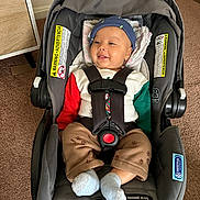 Vivaan joined the competition — help win amazing prizes! baby, infant, child, car_seat, harness, smiling, portrait, indoors, floor, carpet, blue_hat, colorful_clothing, white_socks, seated,  안전, safety_labels, home, head, face, photography