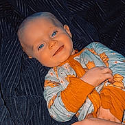 Remington is registered to the contest to win money with this photo: baby, bear_pattern, blanket, blue_eyes, child, cozy, cute, hand, heart_nail_art, indoor, infant, nails, onesie, orange_cuffs, person, portrait, resting, smiling, tender, warm