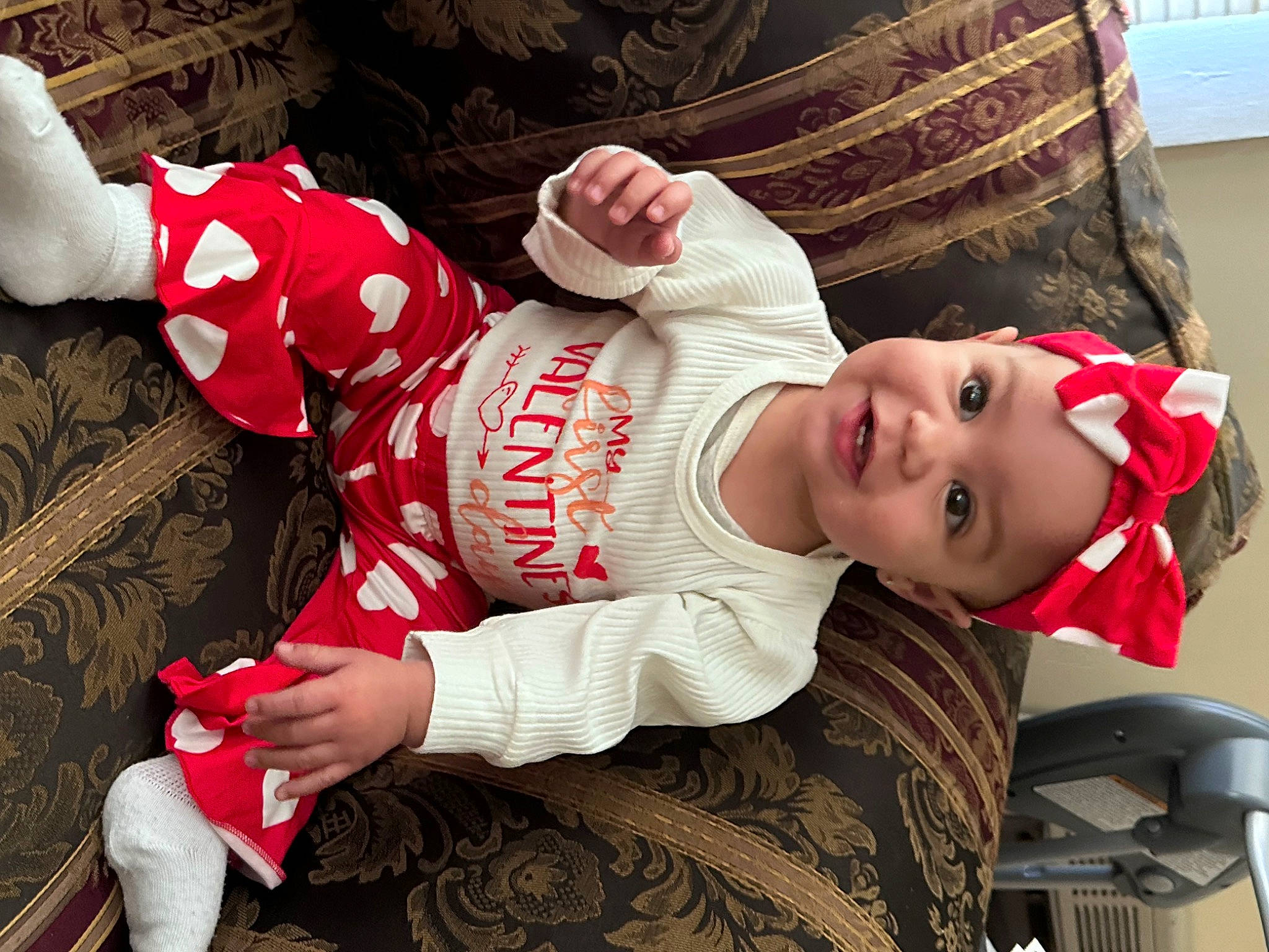 Aiyanna is registered to the contest to win money with this photo: baby, baby_products, baby_toddler_clothing, carmine, child, comfort, fun, happy, headwear, human_leg, lap, mouth, pattern, person, room, sitting, sleeve, smile, sock, t_shirt