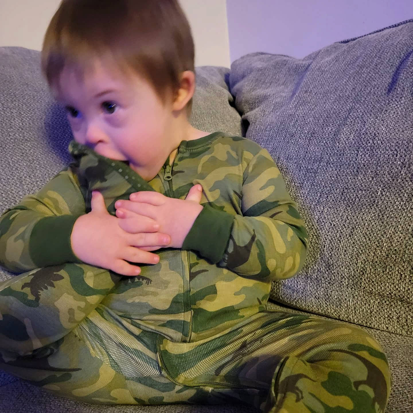 Jackson is registered to the contest to win money with this photo: baby_toddler_clothing, camouflage, cheek, comfort, couch, face, finger, gesture, hair, hand, head, human_body, mammal, military_camouflage, military_person, military_uniform, person, skin, sleeve, surprise