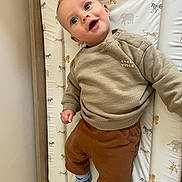 Samuel joined the competition — help win amazing prizes! baby, child, infant, smiling, blue_eyes, beige_sweater, brown_pants, patterned_socks, changing_pad, animal_print, wooden_frame, indoor, cute, happy, portrait, person, clothing, wall, laying_down, baby_bed