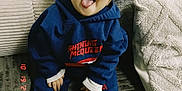 Jasme Marques participe au concours pour gagner de l'argent avec cette photo : toddler, child, blue_hoodie, sneakers, nike_shoes, couch, cushions, tongue_out, smile, indoor, cozy, person, clothing, footwear, baby, happy, sitting, face, cute, playful