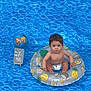 age_marker, baby, background, blue, child, colorful, curious, cute, diaper, floating_ring, globe, indoor, inflatable_ring, person, portrait, sign, sitting, small, water_pattern, young_child