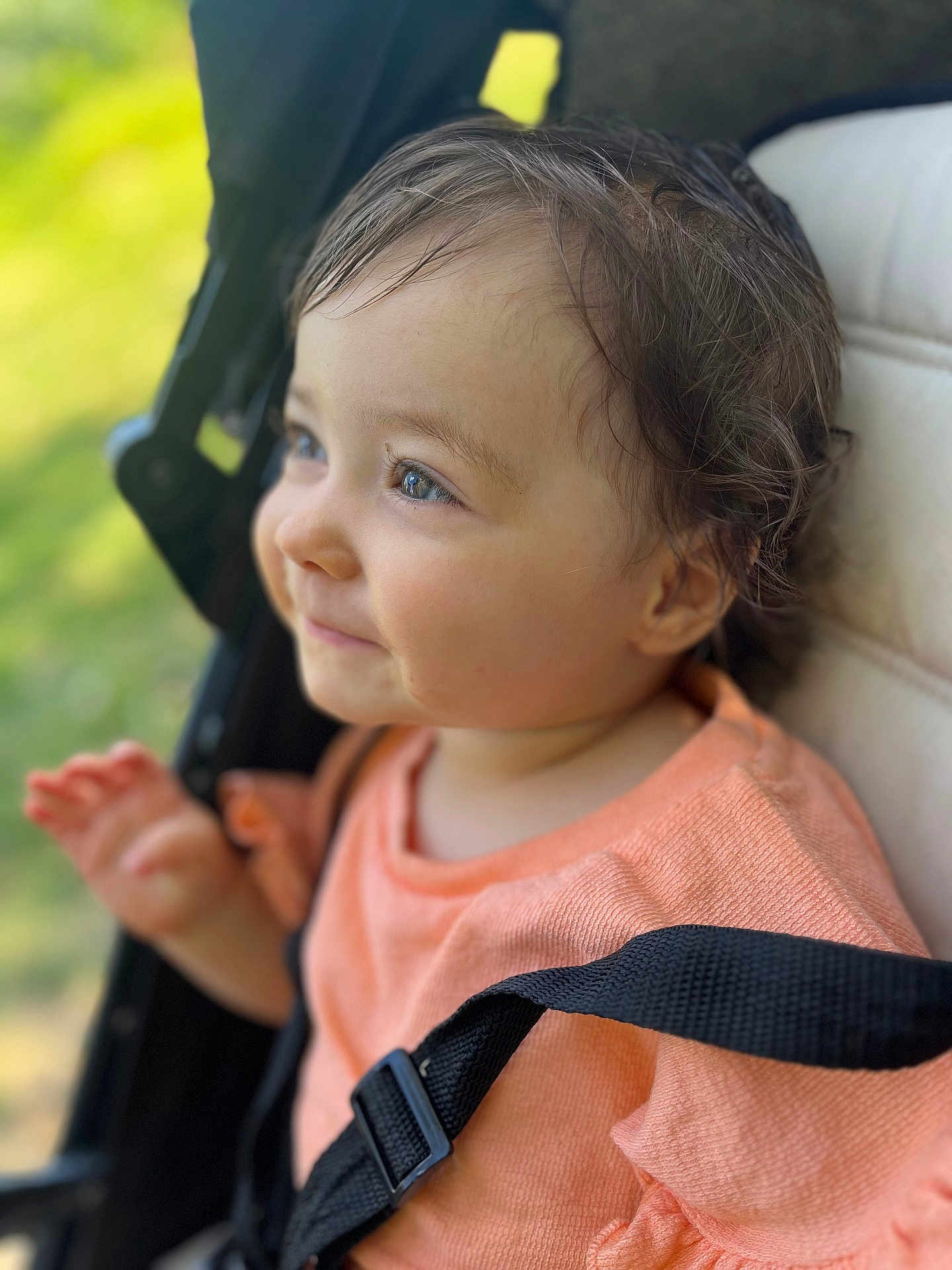 Priya a rejoint le concours — aidez-le/la à gagner de superbes lots ! toddler, child, smiling, face, blue_eyes, curly_hair, stroller, seatbelt, orange_clothing, blurred_background, outdoor, closeup, portrait, happy, baby, person, natural_light, expression, sitting, cute