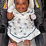Rayne is registered to the contest to win money with this photo: baby, infant, smiling, car_seat, white_dress, mittens, happy, cute, child, footwear, floor, indoor, person, portrait, sitting, clothing, pattern, fabric, head, face