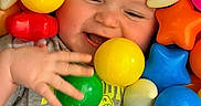 Giovanni is registered to the contest to win money with this photo: baby, bright_colors, casual_clothing, child, closeup, colorful_balls, cute, face, fun, hand, happy, indoor, infant, plastic_toys, playing, playtime, smiling, star_shape, toddler, toy_ball