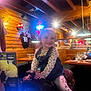 Saylor is registered to the contest to win money with this photo: child, toddler, smile, mechanical_bull, restaurant, wooden_walls, neon_sign, table, glass, menu, clothing, leggings, denim, indoor, lighting, person, happy, sitting, playful, family