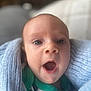 Brewer is registered to the contest to win money with this photo: baby, infant, face, eyes, mouth, blanket, blue_blanket, clothing, green_clothing, expression, surprised, close_up, portrait, indoor, soft_focus, child, skin, head, person, newborn