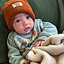 Elijah is registered to the contest to win money with this photo: baby, child, beanie, hat, blanket, sweater, green_chair, indoor, cozy, cute, infant, portrait, clothing, closeup, soft_texture, warm, young_child, face, hand, expression