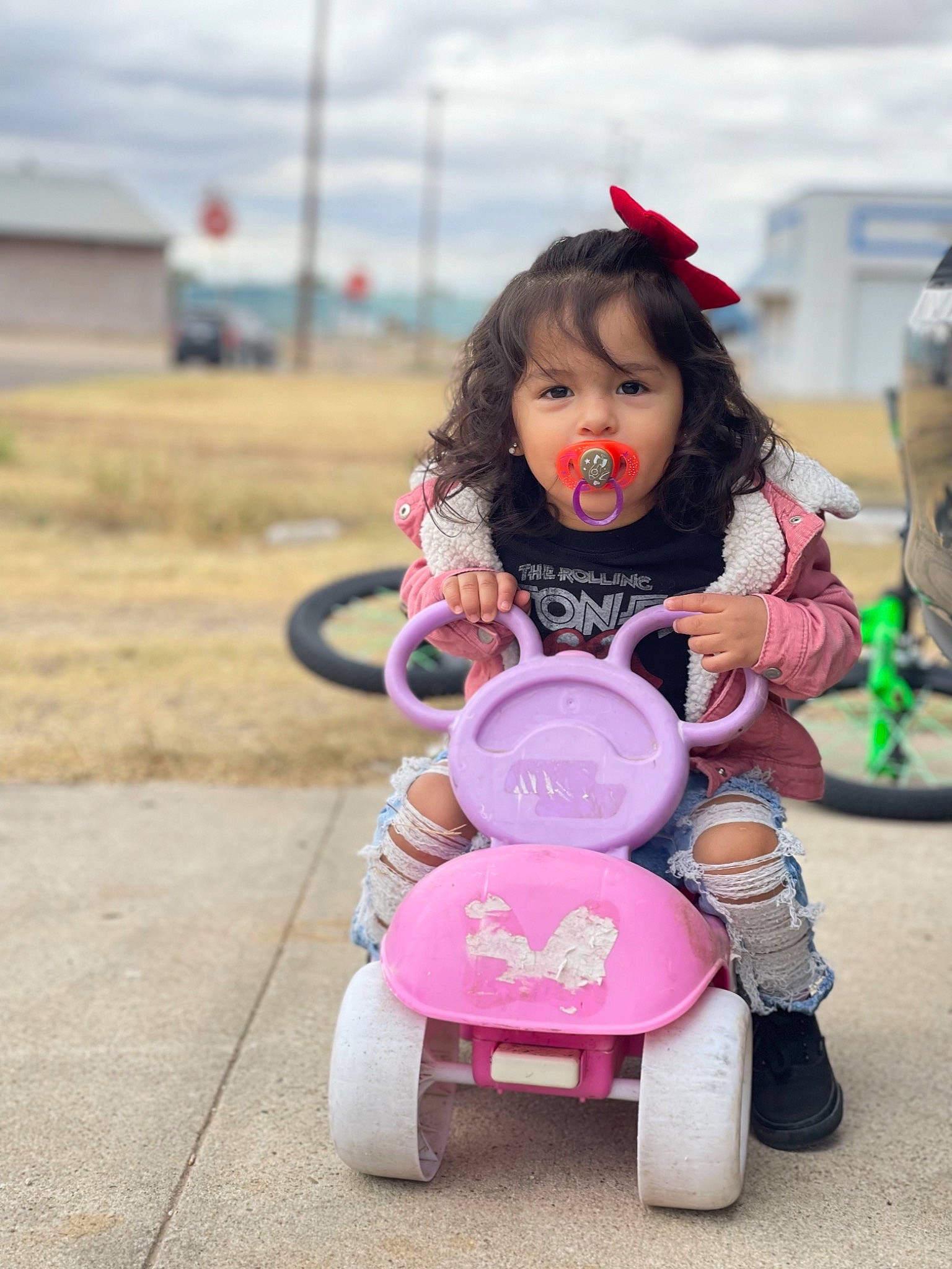 Laramie is registered to the contest to win money with this photo: child, cloud, doll, event, eye, fun, grass, happy, magenta, motor_vehicle, person, pink, recreation, riding_toy, road, sitting, sky, teddy_bear, toddler, toy