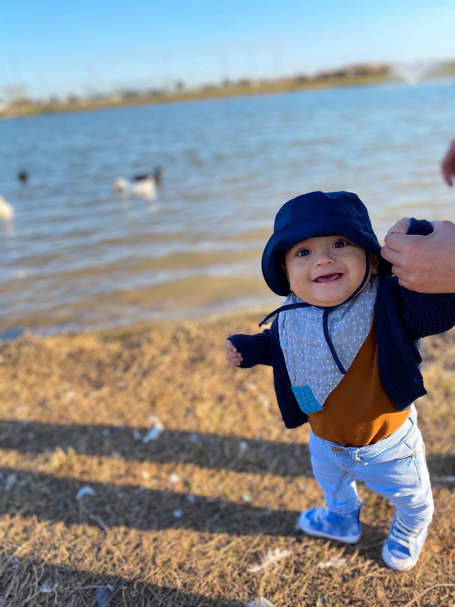 Elian is registered to the contest to win money with this photo: azure, baby_toddler_clothing, beach, body_of_water, cap, happy, hat, headgear, headwear, joy, lake, landscape, leisure, morning, natural_environment, people_in_nature, person, sky, smile, sunlight