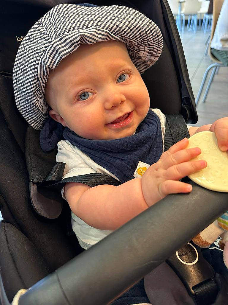 Mahe participe au concours pour gagner de l'argent avec cette photo : baby, baby_carriage, cap, chair, cheek, child, cool, eye, face, facial_expression, finger, fun, gesture, happy, headwear, organ, people, person, skin, smile