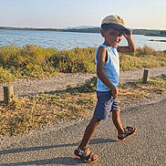 Eïden a rejoint le concours — aidez-le/la à gagner de superbes lots ! child, boy, smile, cap, tank_top, shorts, sandals, walking, outdoor, lake, water, nature, grass, path, sunlight, shadow, summer, happy, landscape, casual