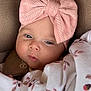 baby, infant, face, headband, pink, blanket, floral_pattern, closeup, child, cute, soft_texture, knitwear, resting, indoors, portrait, young, wrapped, comfort, peaceful, expression