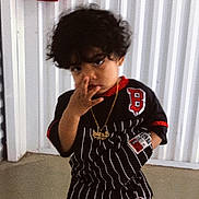 John Axziel is registered to the contest to win money with this photo: black_clothing, casual, child, confident, curly_hair, face, fashion, fire_extinguisher, floor, gold_chain, hand, head, indoor, person, pose, shorts, standing, striped_outfit, wall, young_child