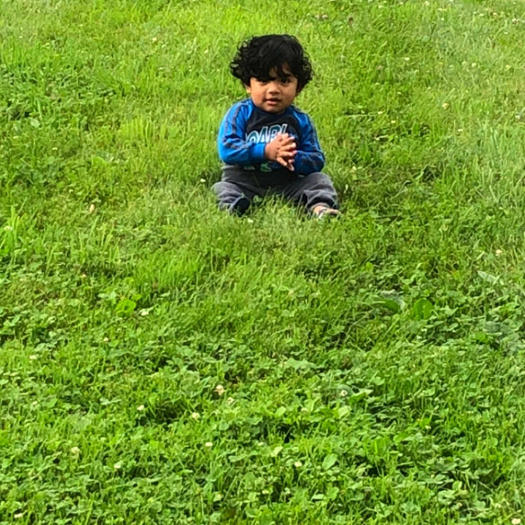 John Axziel joined the competition — help win amazing prizes! alone, casual, casual_clothing, child, clapping_hands, curly_hair, daylight, field, grass, grass_field, greenery, kid, nature, outdoor, park, person, portrait, relaxing, sitting, young