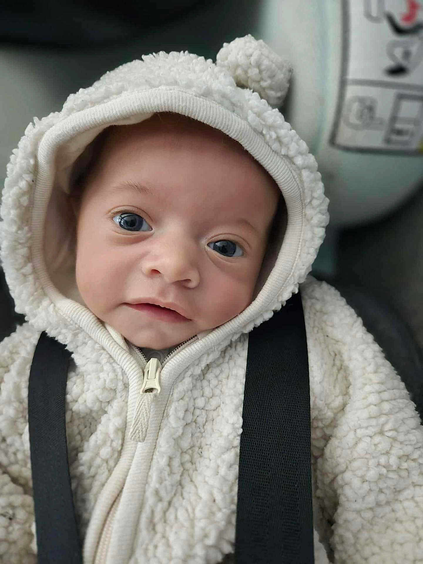 Eden a rejoint le concours — aidez-le/la à gagner de superbes lots ! baby, infant, hoodie, white, fluffy, pom_pom, face, blue_eyes, close_up, cute, young_child, straps, clothing, portrait, child, warm_clothing, indoors, soft_texture, looking_at_camera, adorable