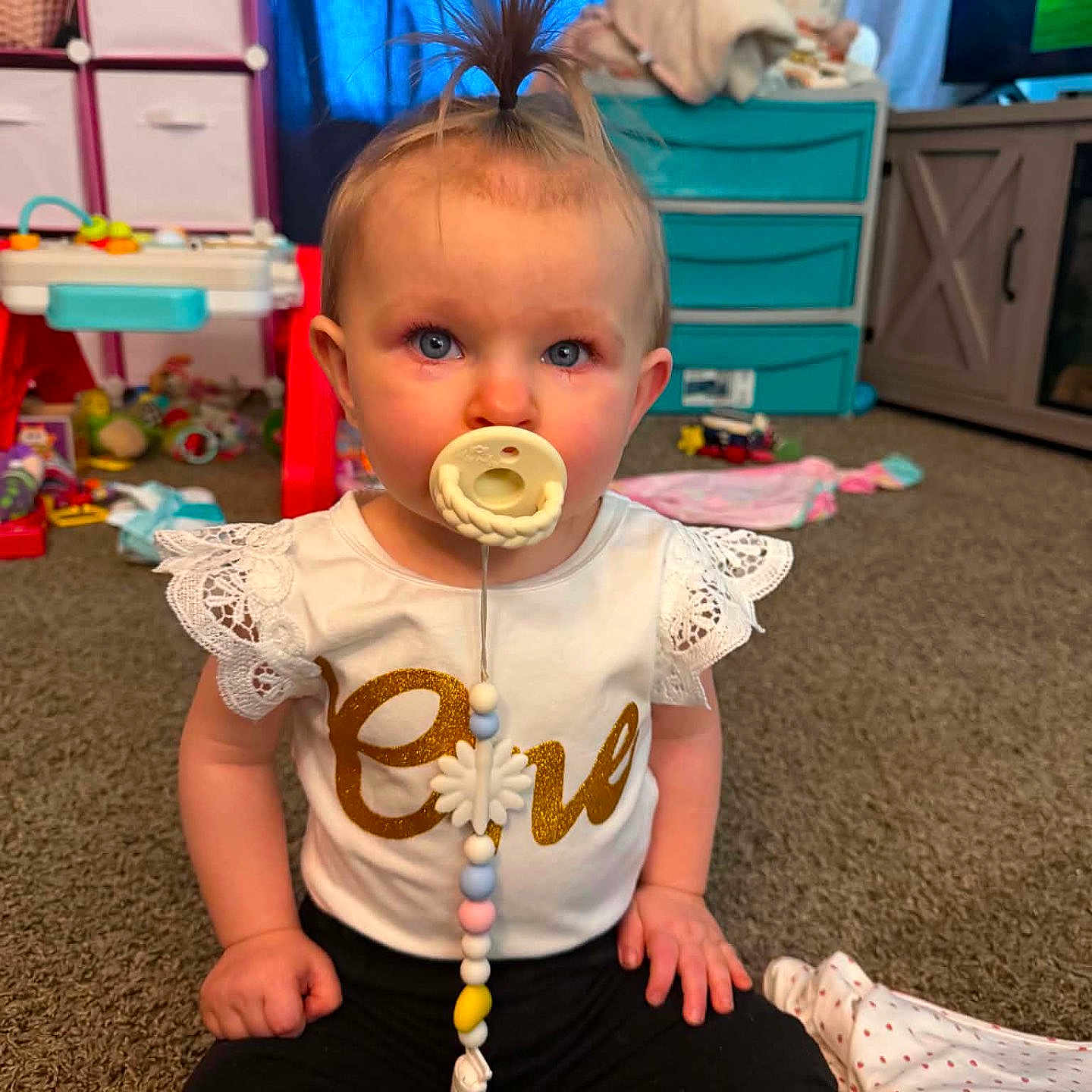 Nova is registered to the contest to win money with this photo: baby, child, pacifier, sitting, toy, carpet, indoor, furniture, blue_eyes, hair, clothing, cute, playroom, storage, drawer, curious, person, floor, room, home