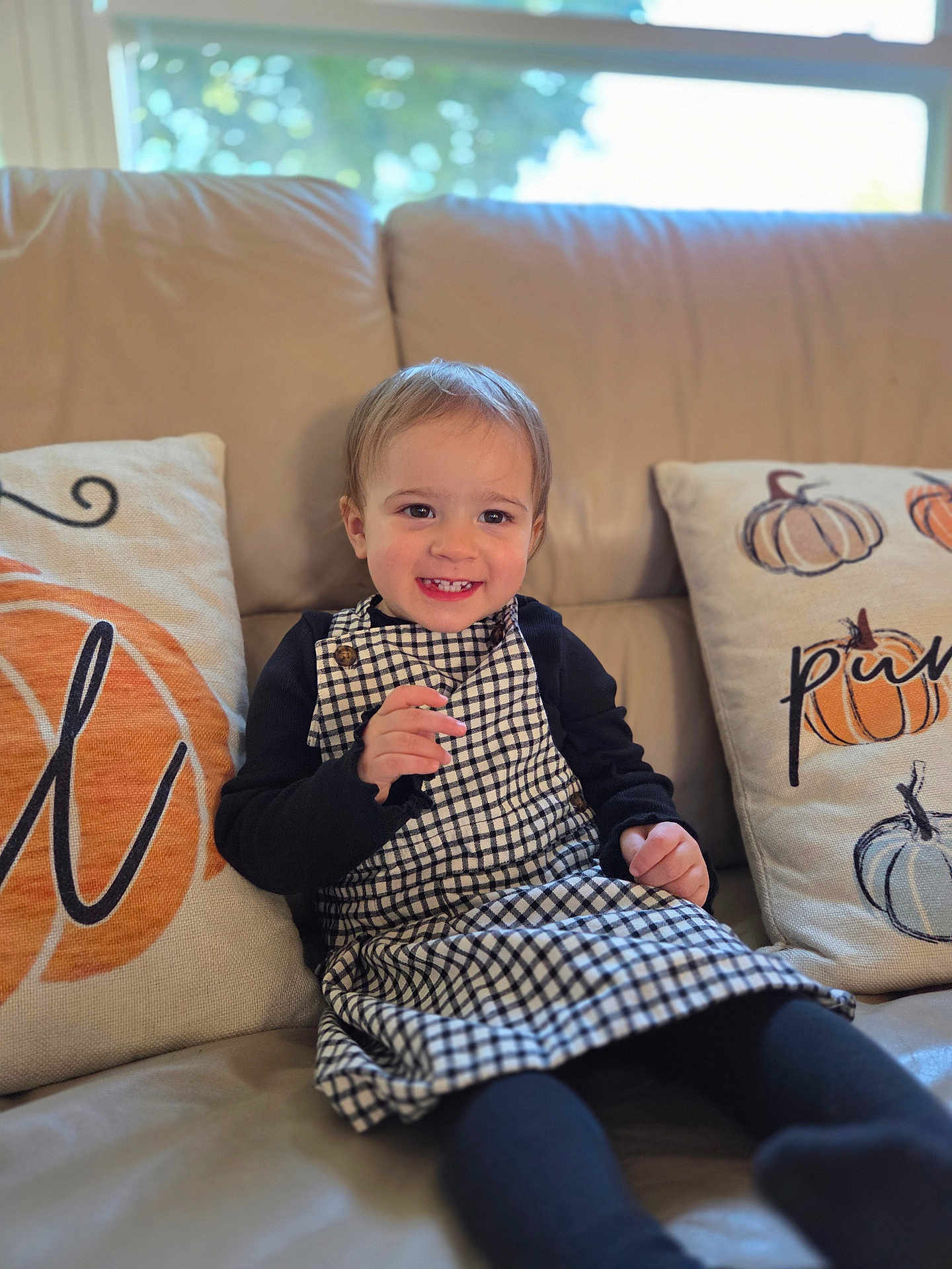 Vana joined the competition — help win amazing prizes! toddler, child, smiling, sitting, couch, pillows, pumpkin, window, indoor, clothing, dress, black_sleeves, happy, face, hair, home, cozy, natural_light, cute, portrait
