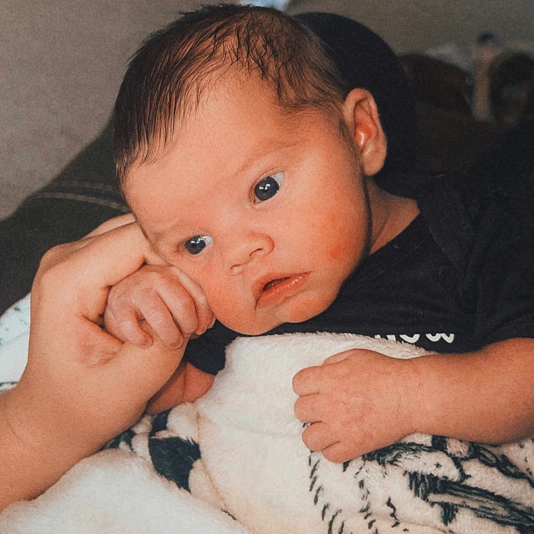 Hesston is registered to the contest to win money with this photo: accessories, baby, bed, blanket, bodypart, clothing, face, finger, hand, happy, head, indoors, newborn, person, photography, portrait, quilt, smile, t_shirt, towel