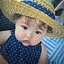 baby, child, hat, straw_hat, polka_dot, dress, navy_blue, face, eyes, curly_hair, hand, striped_shirt, adult, person, portrait, close_up, indoors, cute, holding, fashion