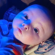 Houston is registered to the contest to win money with this photo: baby, infant, face, closeup, blue_light, blanket, curious, eyes, soft_light, indoors, child, portrait, young, cute, sleepwear, expression, skin, head, person, cozy