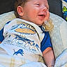 baby, infant, child, smiling, sleepy, portrait, pacifier, blanket, football, sports_fan, lions, onesie, blue_clothing, lying_down, cozy, indoor, chair, cushion, close_up, happy